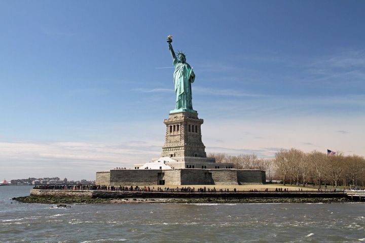 Statue of Liberty on Liberty Island with blue sky and people around