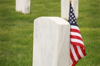 Gravestone with American flag in a cemetery row on green grass.