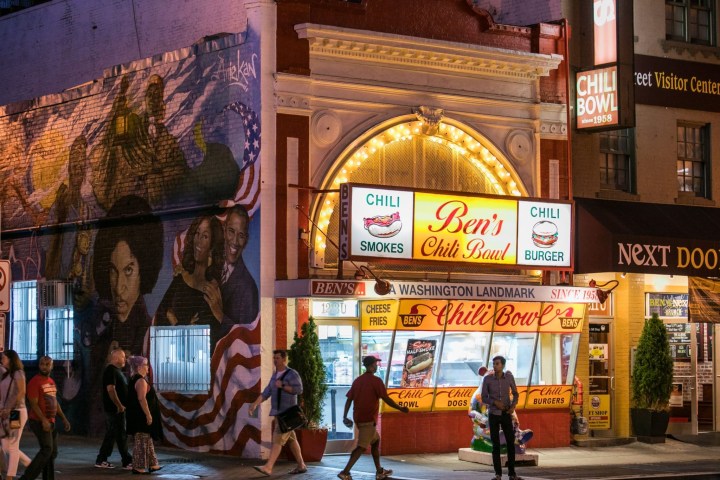 Night view of Ben's Chili Bowl with mural and people walking by in Washington, D.C.