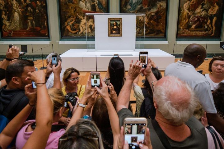 Crowd taking photos of the Mona Lisa in a museum gallery
