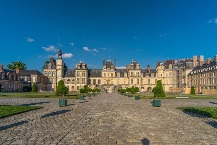 Grand historic building with central clock tower and landscaped courtyard.