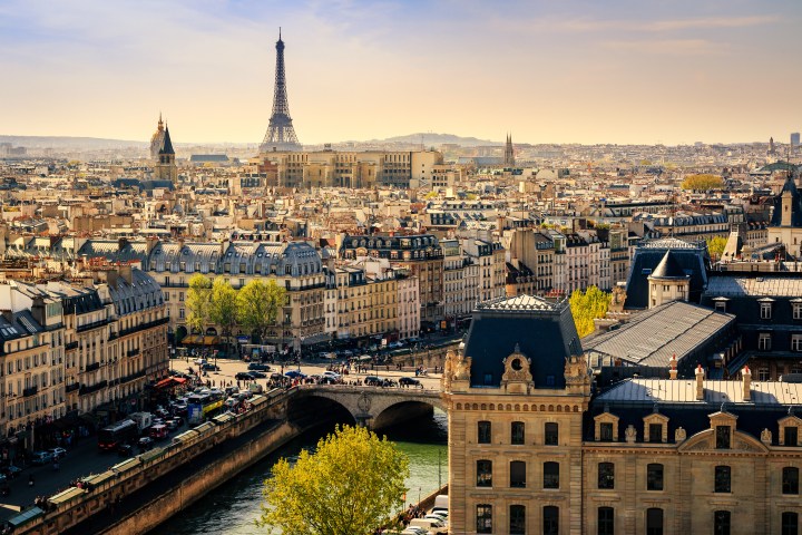 Aerial view of Paris with Eiffel Tower and Seine River under a clear sky.