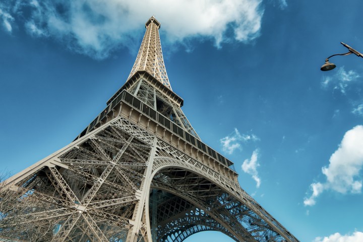 View of the Eiffel Tower from below against a blue sky with clouds.
