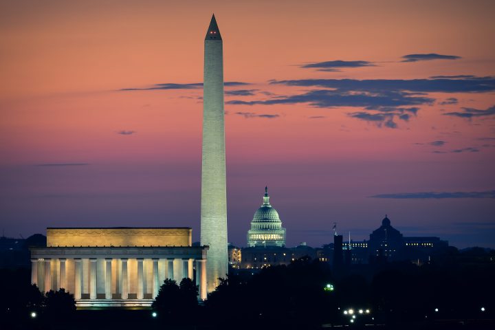 Washington, D.C. skyline at dusk with lit monuments and colorful sky.