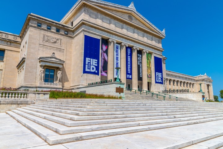 Stone building with columns, large banners, and wide steps under a clear blue sky.