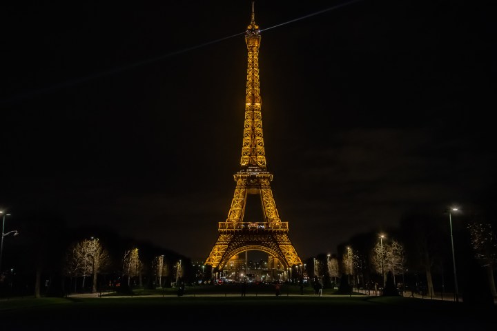 Eiffel Tower illuminated at night with lights and dark sky.