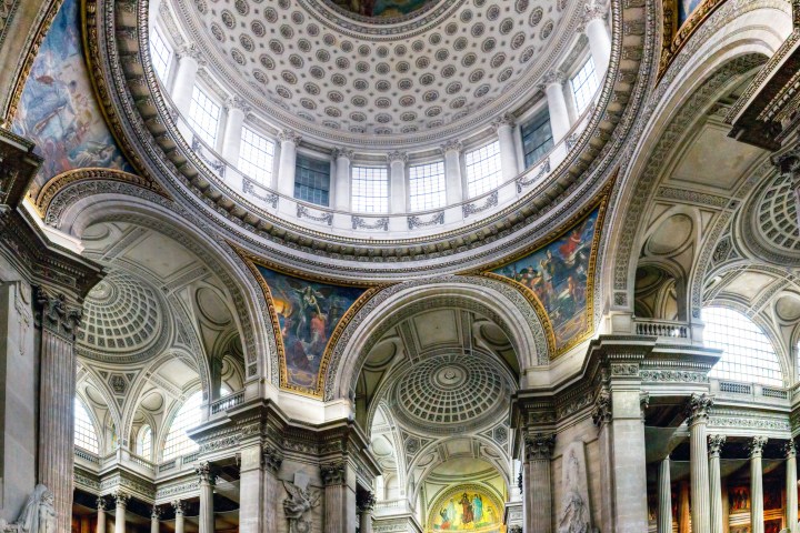 Elegant cathedral interior with intricate arches, columns, and a painted dome ceiling.