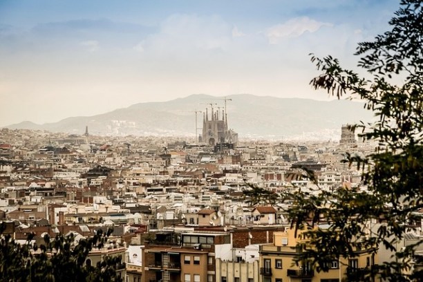 Aerial view of a cityscape with a large cathedral and mountains in the background.