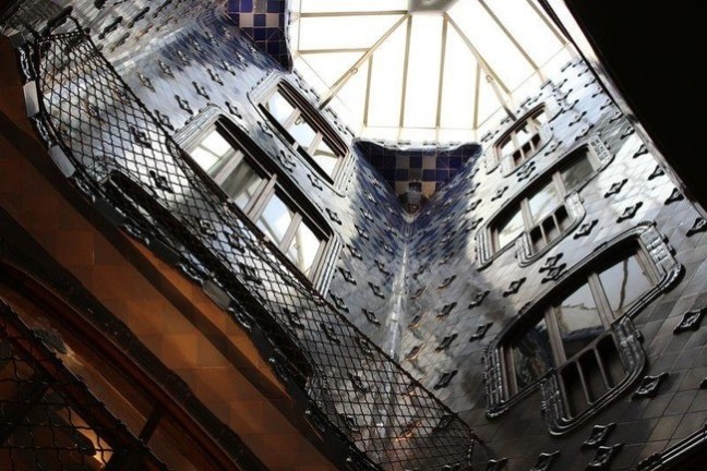Interior atrium with blue tile walls and skylight, featuring decorative metalwork and windows.