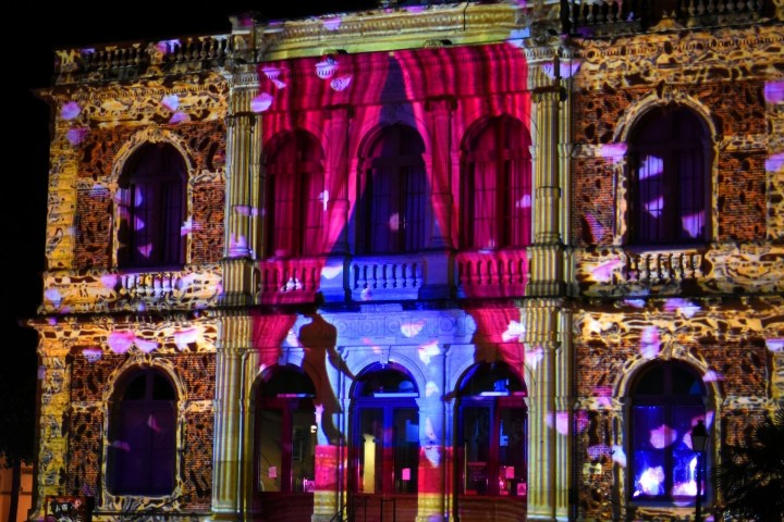 Historic building facade with colorful light projections at night.
