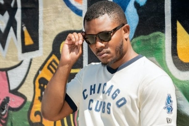 Man in sunglasses wearing a Chicago Cubs shirt in front of colorful graffiti.