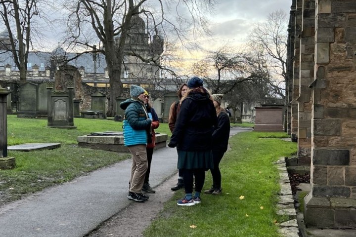 Group of people talking in a cemetery with overcast sky in the background.