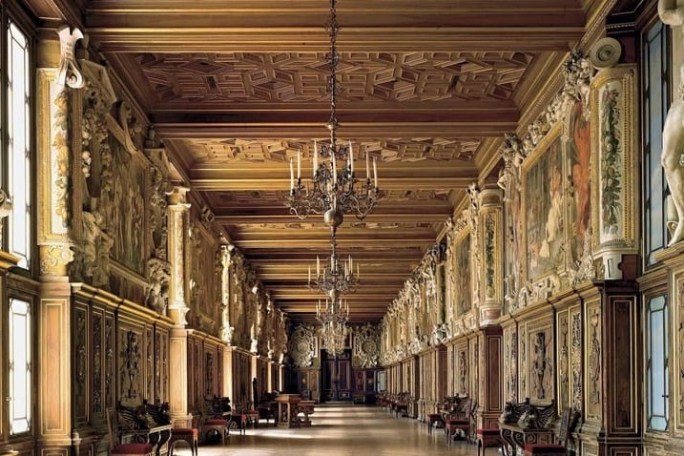 Ornate hall with high ceilings, chandeliers, and detailed wall carvings and paintings.