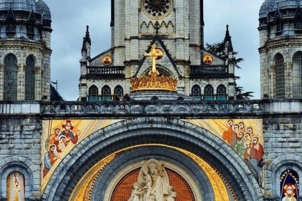 Ornate church facade with mosaic, arched entrance, towers, and cross.