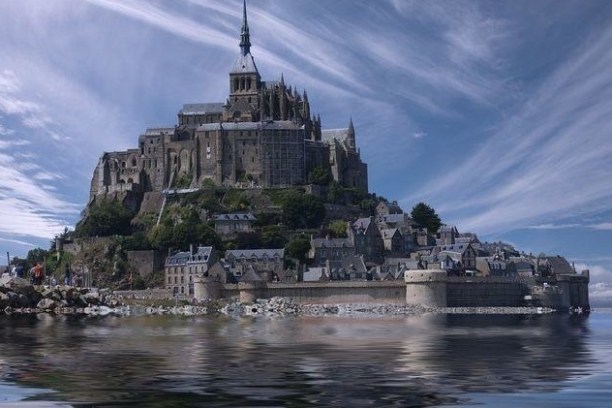 Castle on island surrounded by water with dramatic sky and wispy clouds.