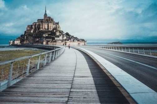 Pathway leading to a distant castle with cloudy skies in the background.
