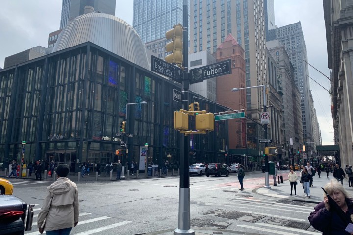 Street view of intersection near Fulton Center with skyscrapers and people walking.