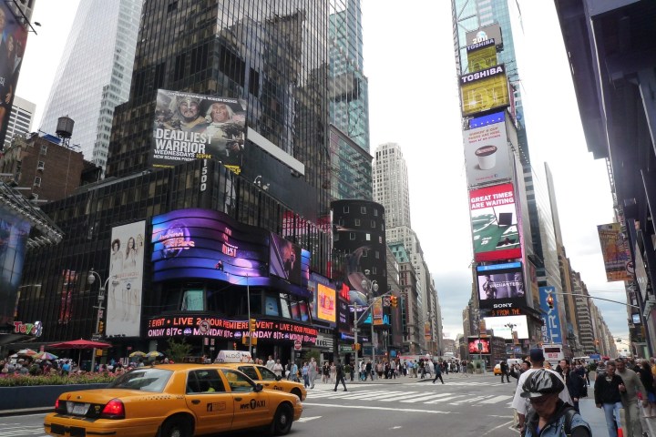 Times Square street view with billboards, yellow taxi, and pedestrians