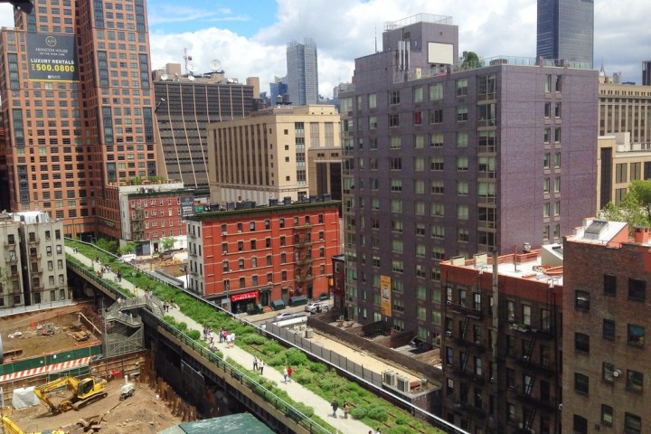 Urban scene with elevated park, buildings, and construction site.