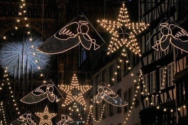 Street decorated with angel and star-shaped lights during nighttime festival.