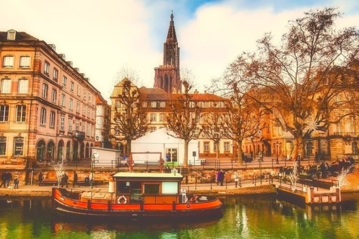 Historic buildings and a boat on a canal with a church tower in the background.