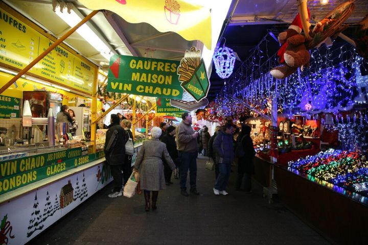People at a festive market with food stalls and decorative lights.