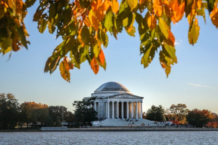 Jefferson Memorial with autumn leaves and water in the foreground.