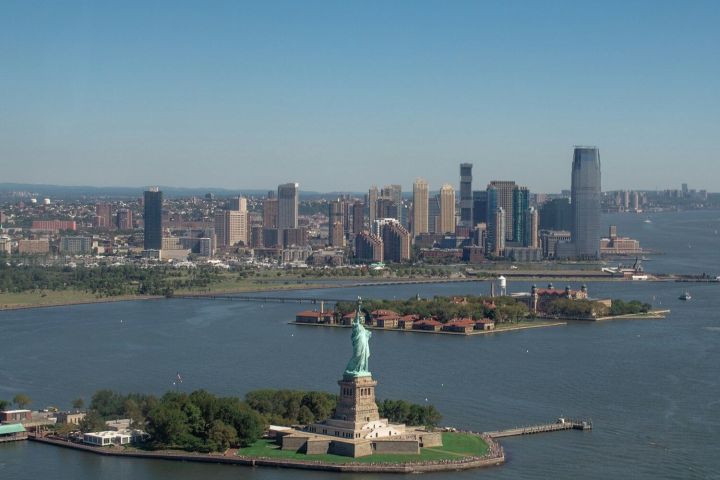Aerial view of the Statue of Liberty with the New Jersey skyline in the background.