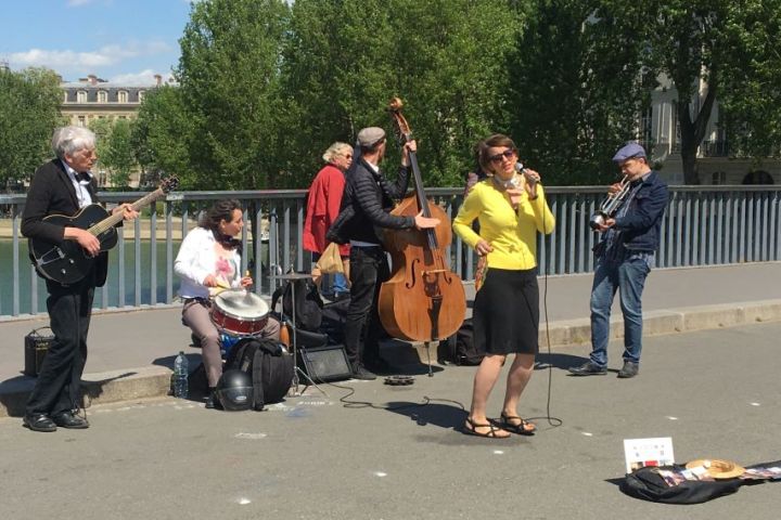 Street band playing music on a sunny day with trees in the background.