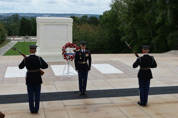 Guard ceremony at the Tomb of the Unknown Soldier, with soldiers in uniform and a wreath in front.