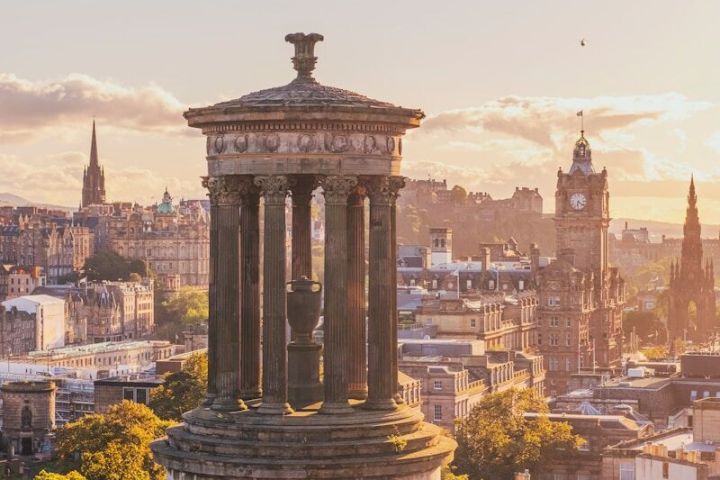 Monument with columns on hill overlooking city at sunset.