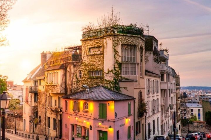 Sunset over a cobblestone street with a pink building and ivy-covered walls.