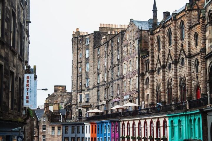 Colorful buildings line a curved cobblestone street on a cloudy day.