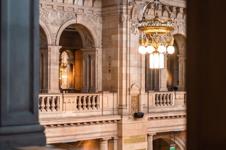 Ornate chandelier in a historic building with arches and large windows.