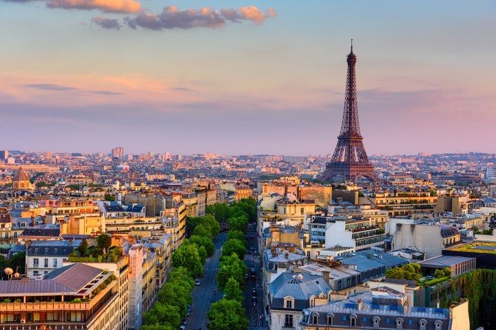 Eiffel Tower in Paris skyline at sunset with colorful sky and city rooftops.