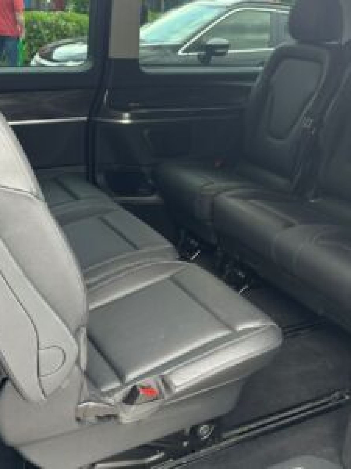 Interior of a van with black leather seats and sliding door open.