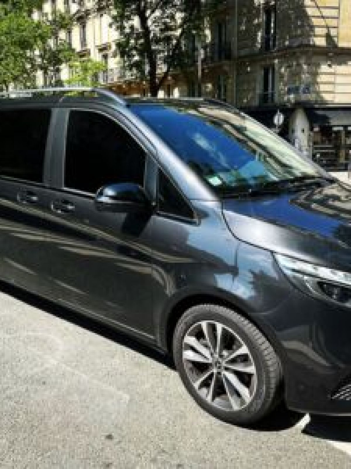 Gray van parked on a sunny street with Parisian buildings in the background.