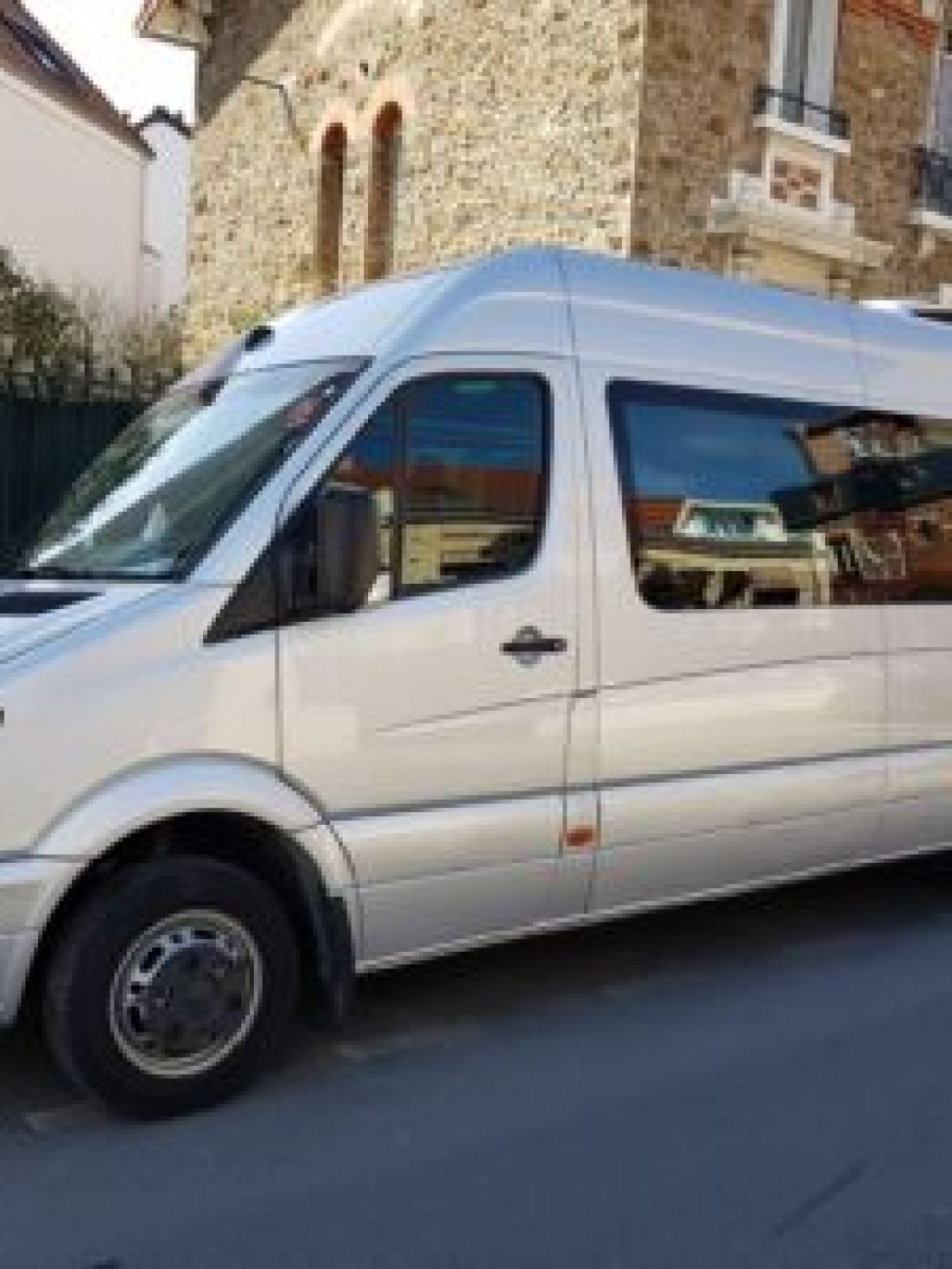 Silver van parked on a residential street beside brick buildings.