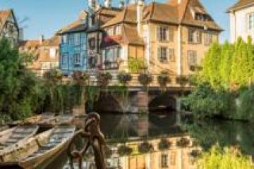 Scenic canal with colorful half-timbered houses and small boats in a quaint European town.