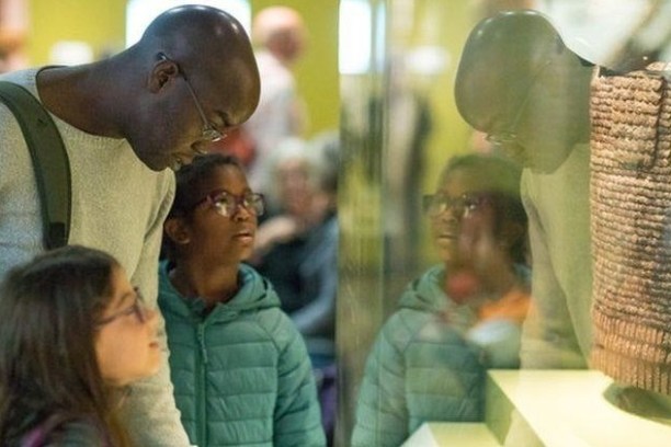 Three people looking at a museum display through a glass case.