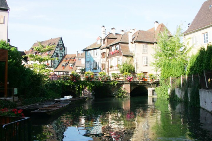 Picturesque canal with boats, floral bridge, and charming European houses.