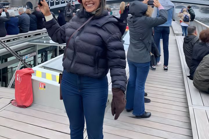 Smiling person in a puffy jacket on a crowded walkway taking photos.