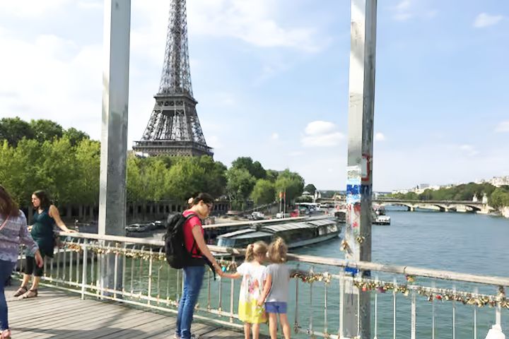 People on a bridge overlooking the Eiffel Tower and Seine River in Paris.