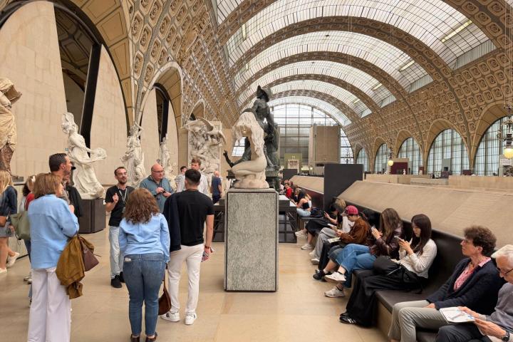 People in a museum gallery with sculptures and an arched ceiling.