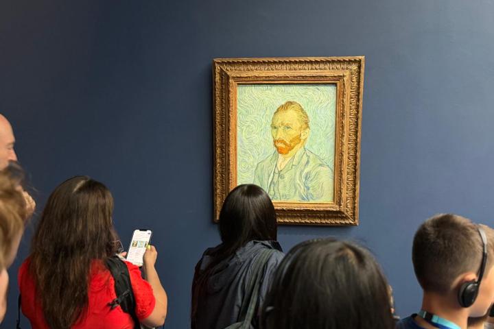 People viewing Van Gogh portrait in a museum.